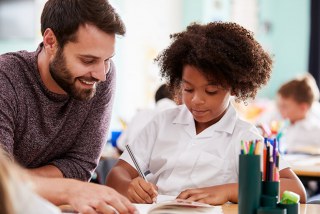 Male teacher teaching a student in uniform