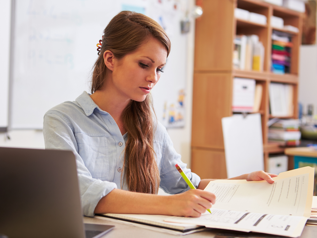 young teacher writing reports at desk